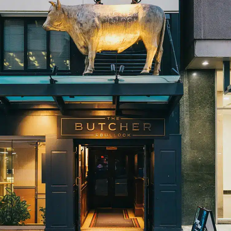Picture of a gold bull statue above the doorway of the restaurant The Butcher and Bullock Public House